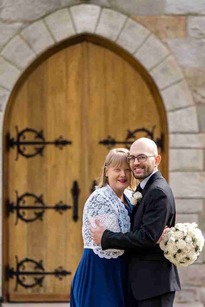 Bride and groom smiling in front of a church door.