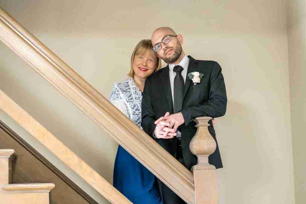 A couple dressed in formal attire posing on a staircase.