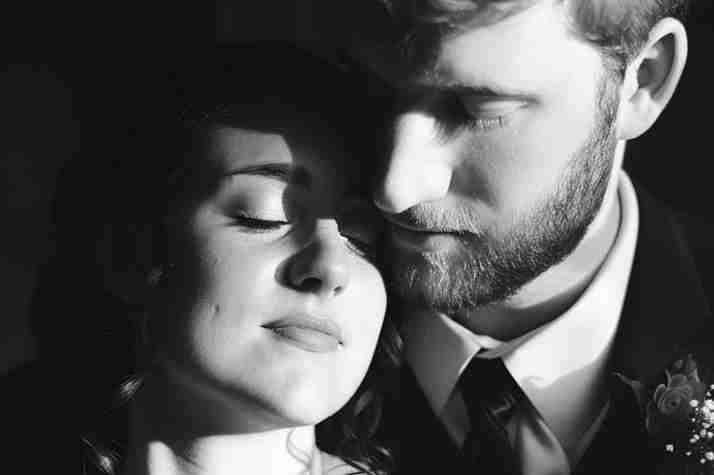 Groom looking over bride with eyes closed in a black and white photo