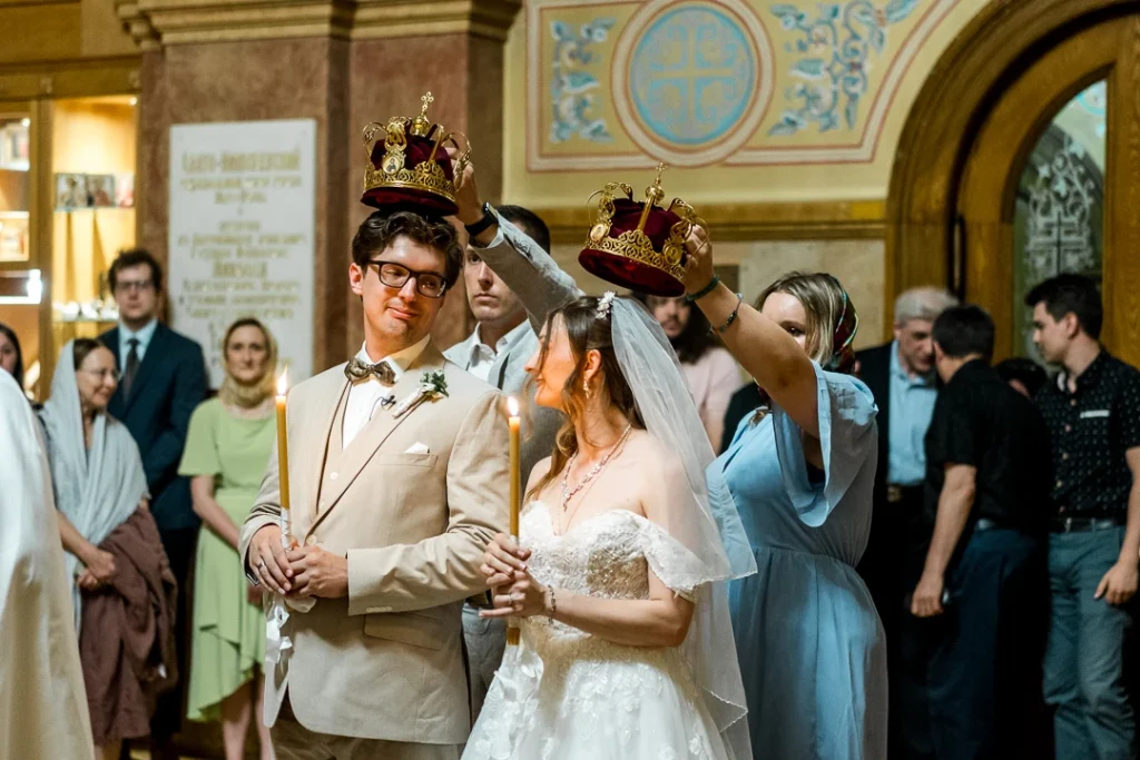 Bride and groom, looking at each other while they're crowns over their heads