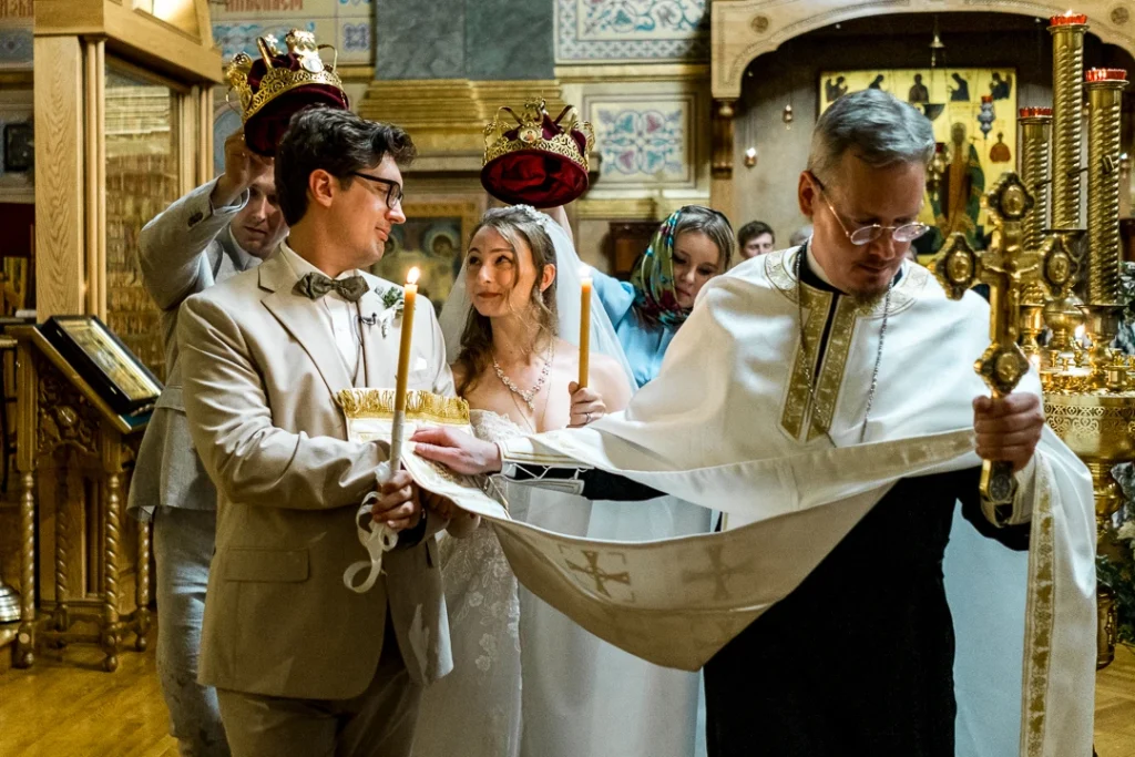 Bride and groom, looking at each other, holding candles while they're walking in circles in church