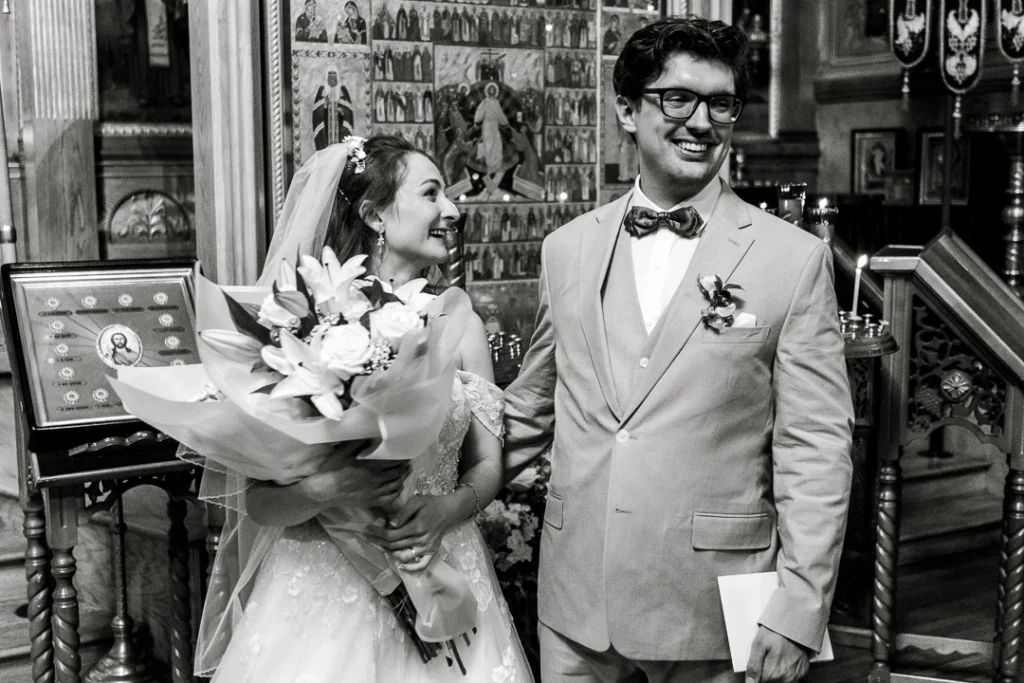 Bride holding flowers, looking at groom groom, looking at guests