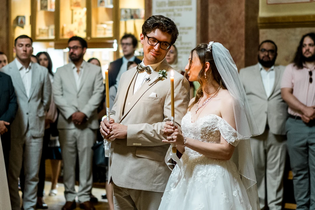 Bride and groom, looking at each other while holding candles in church