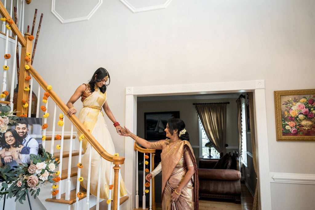 Guiding Steps: A touching moment as the bride descends the staircase, guided by her mother, symbolizing the journey she is about to embark on.