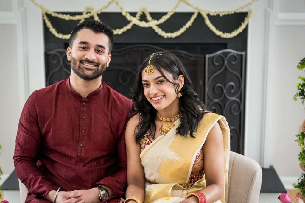 Engagement Ceremony: The bride and groom seated together amidst the ritual, surrounded by intricate floral decorations, capturing the essence of their union.
