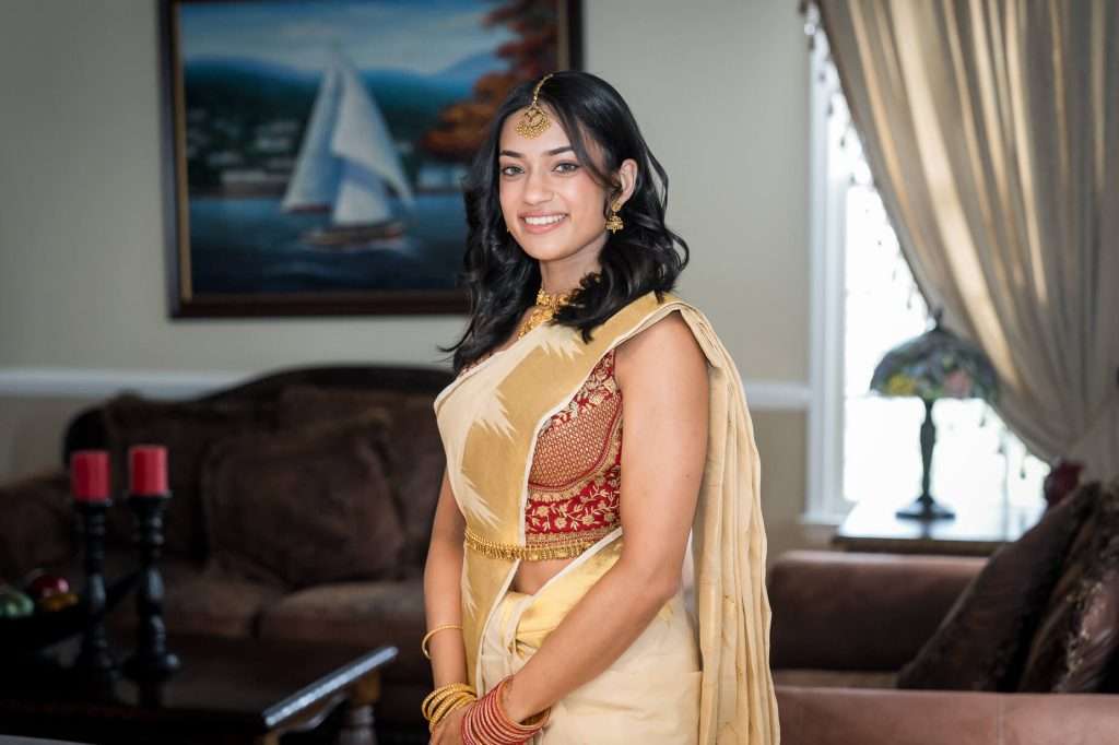 Elegant Poise: The bride stands confidently with a soft smile, adorned in traditional jewelry and a beautifully embroidered saree.