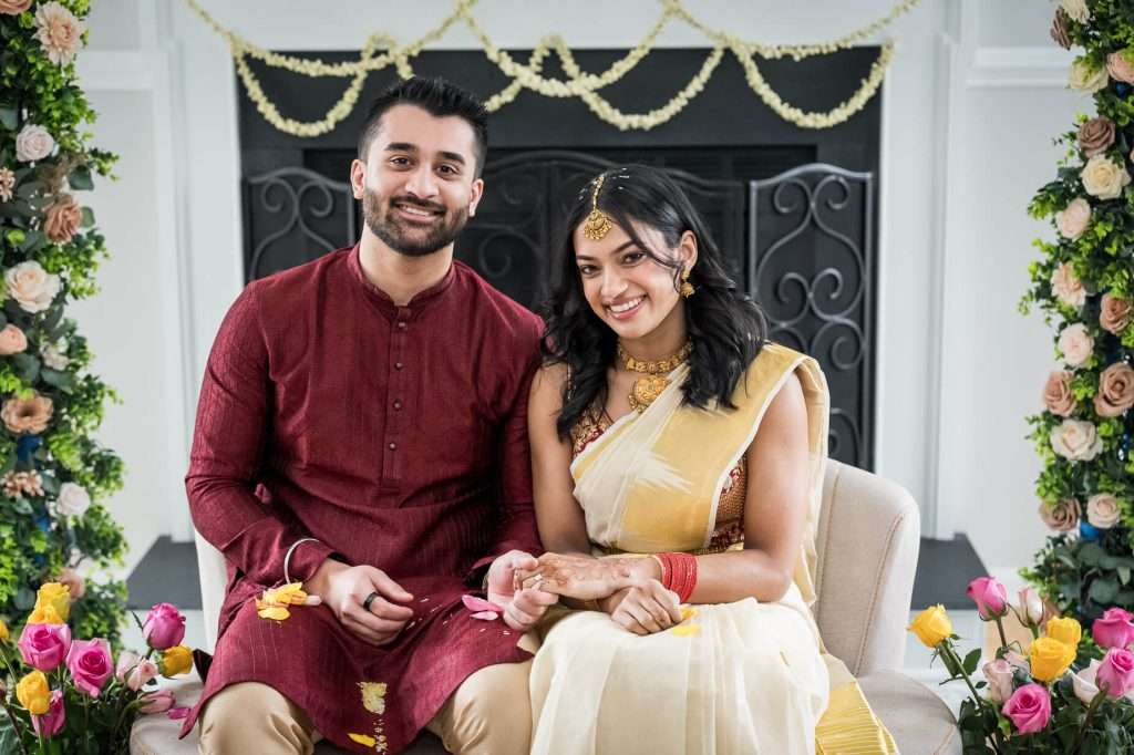 Couple in Traditional Attire: Captured in a serene moment, this couple radiates joy and elegance in traditional Indian attire during their engagement ceremony, surrounded by delicate floral decorations.