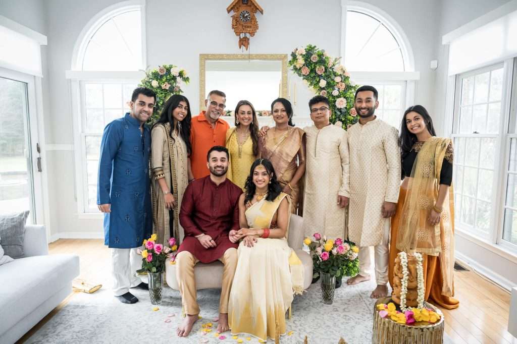 Family Group Portrait: A family comes together to celebrate love at an Indian engagement ceremony, captured in a group portrait that exudes warmth and unity.