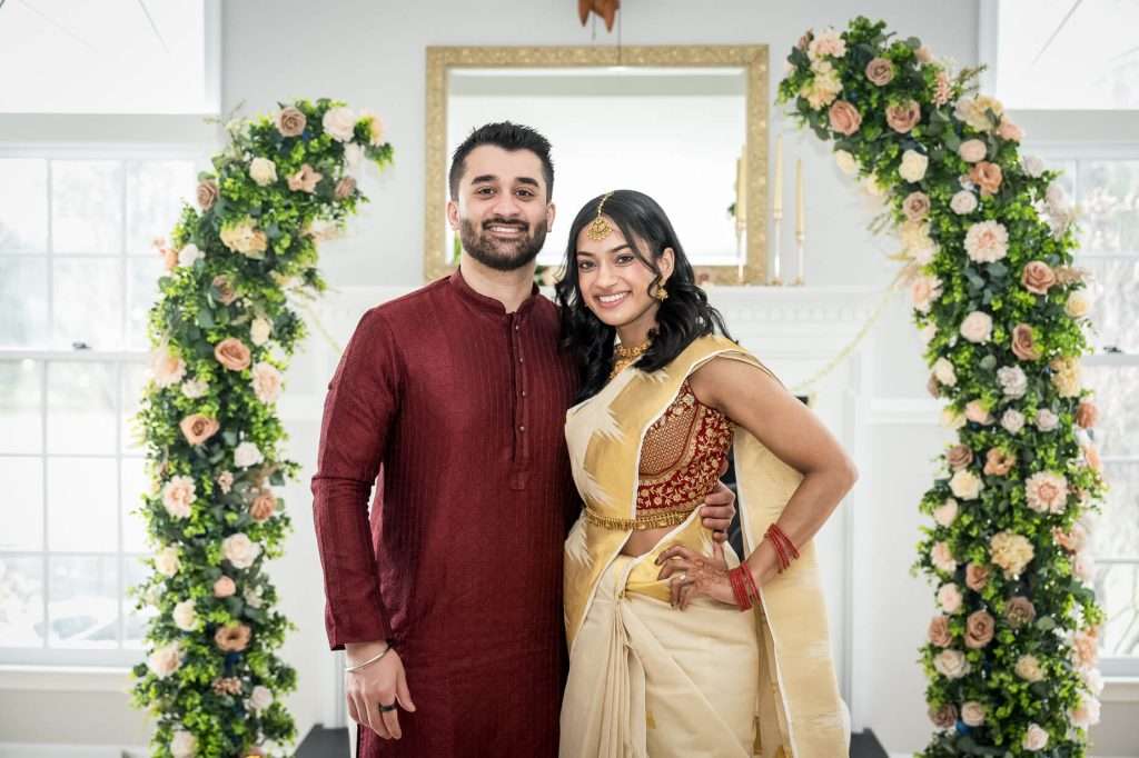 Couple’s Portrait with Floral Arch: This charming portrait of the engaged couple, framed by a stunning floral arch, captures their happiness and the exquisite detail of their traditional outfits.
