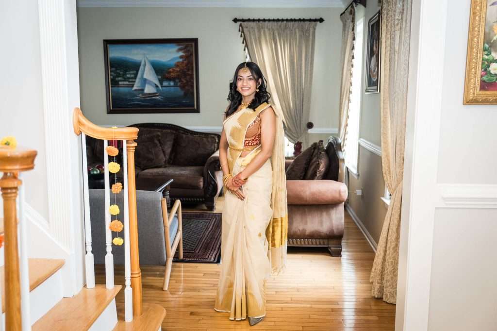 Regal Stance: A full-length portrait of the bride in a richly decorated living room, showcasing her elegant traditional attire and poised demeanor.