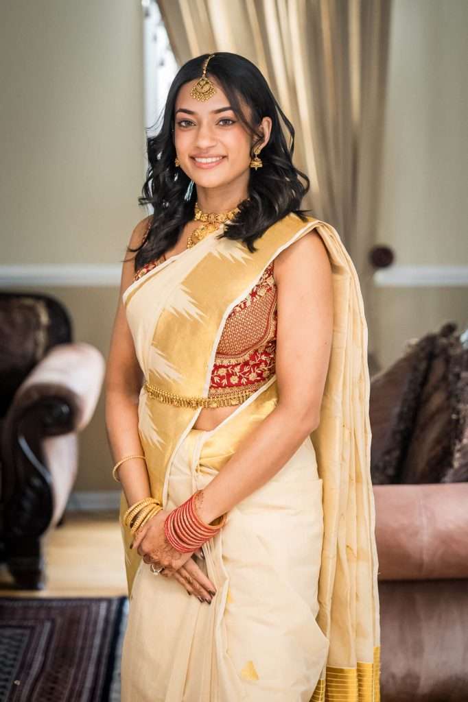 Classic Elegance: The bride poses with a gentle smile, her traditional jewelry glistening against her detailed saree.