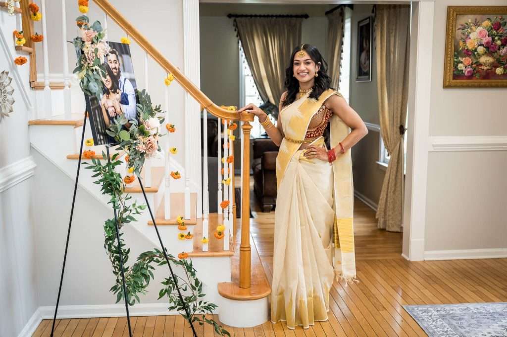 Stylishly Traditional: The bride stands by the staircase, her outfit perfectly complementing the warm, inviting decor of the house.