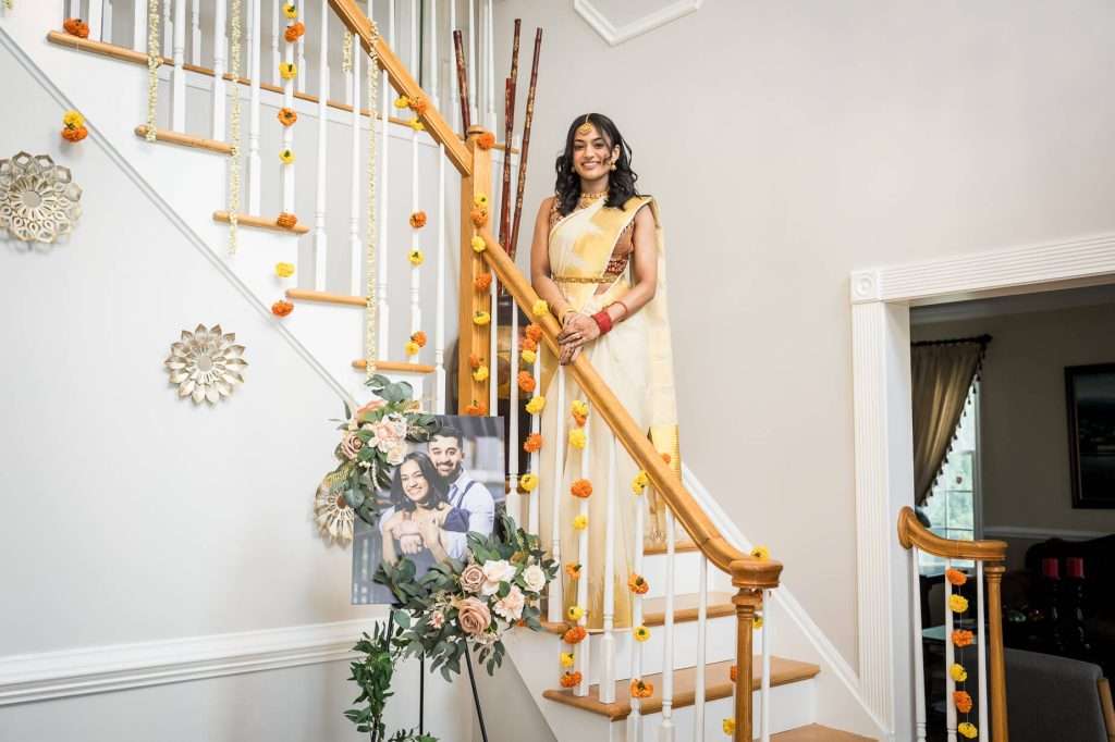 Cultural Radiance: A joyful bride poses with traditional decor in the background, her attire and accessories reflecting her cultural heritage.