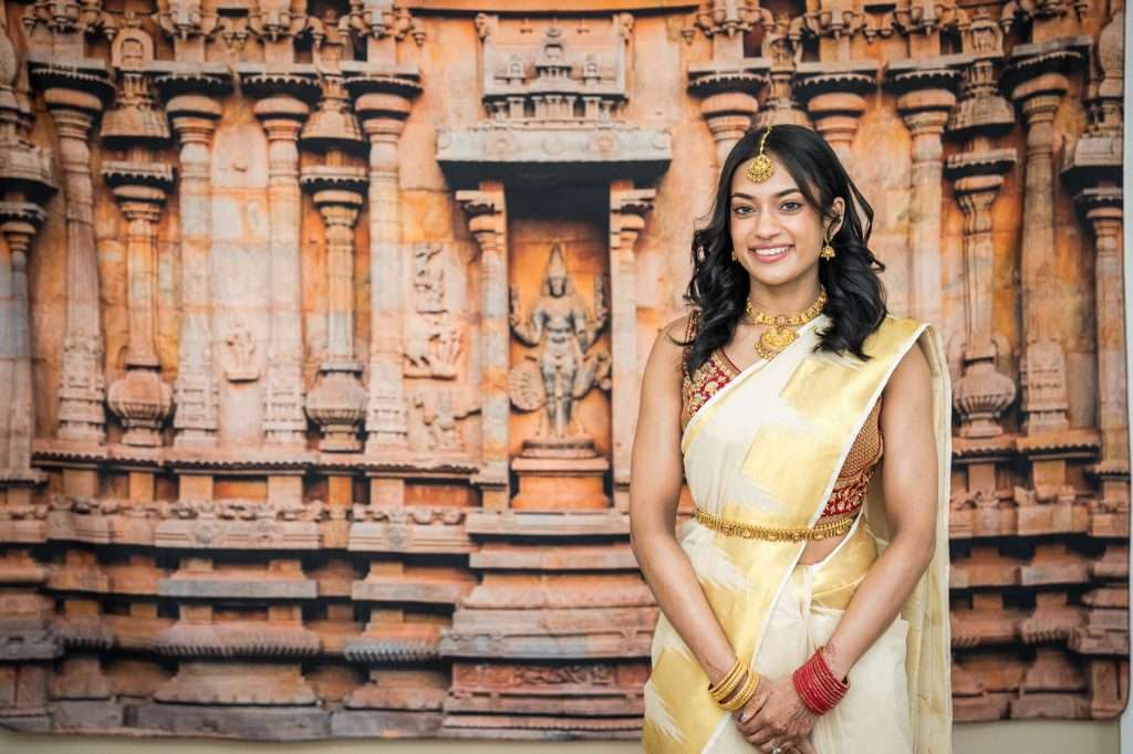 Symbolic Backdrop: The bride stands before a stunning mural of an ancient temple, symbolizing the deep cultural roots of the engagement ceremony.