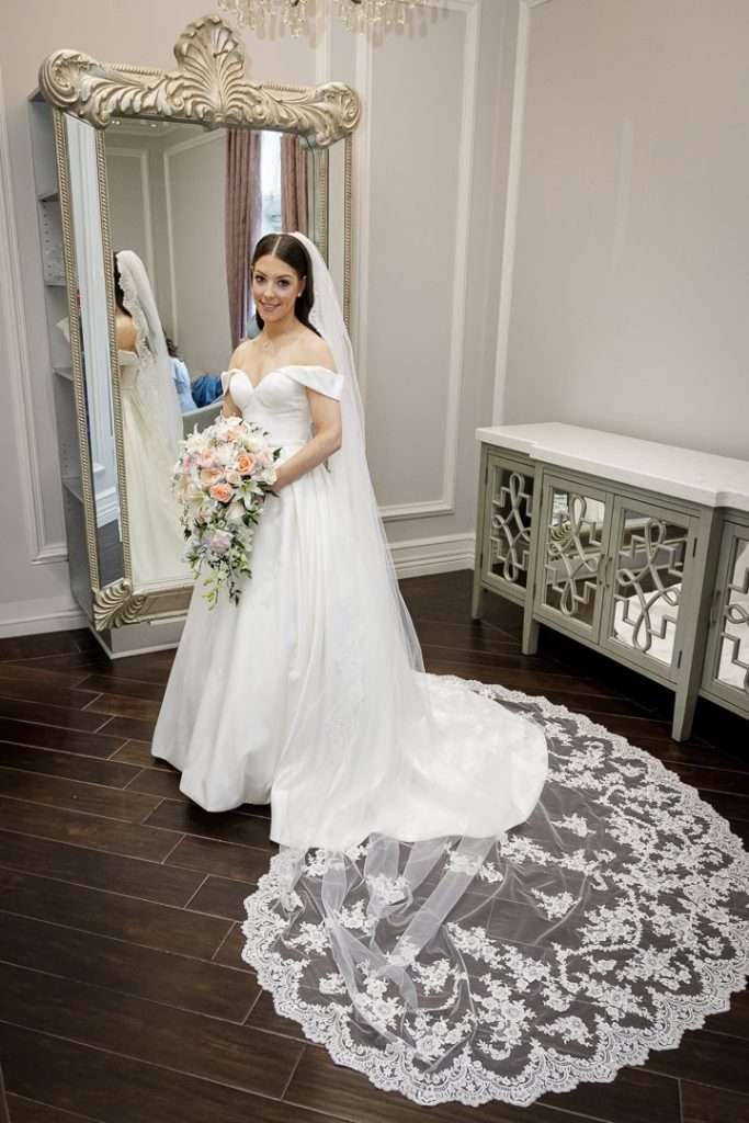  The bride poses in front of a grand mirror in her wedding gown at The Rockleigh.