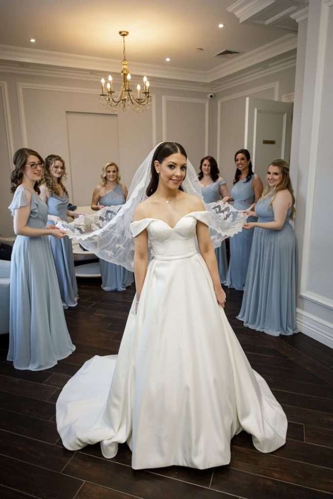 The bride stands joyfully with her bridesmaids as they spread her veil in The Rockleigh’s luxurious bridal suite.