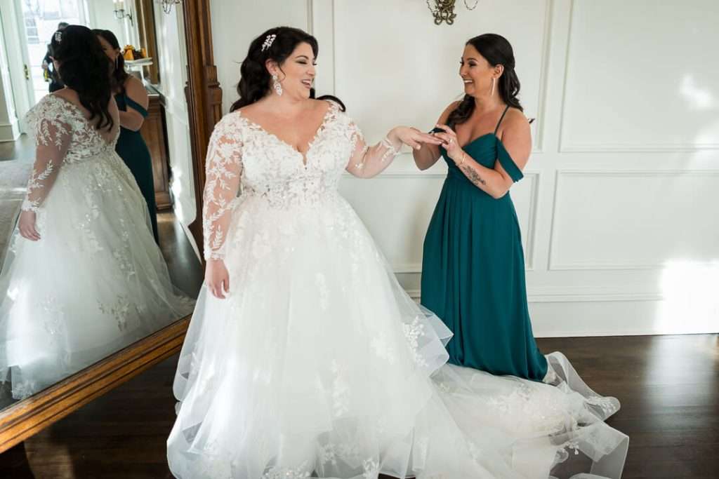 The bride, in a stunning lace wedding gown, shares a special moment with her bridesmaid at The Park Savoy Estate.