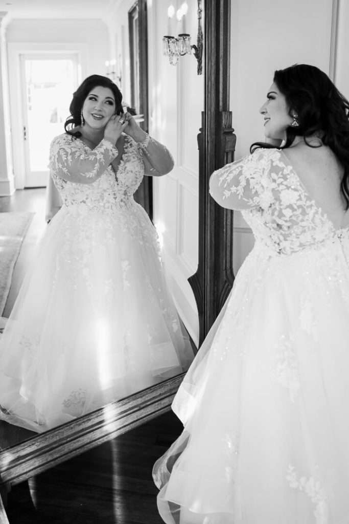 The bride admires her reflection while putting on earrings before her wedding at The Park Savoy Estate.