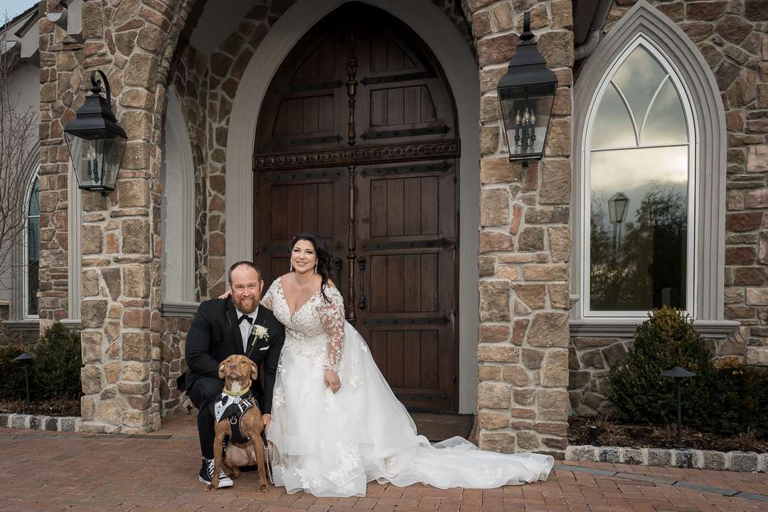 Bride and groom pose with their dog outside the chapel at The Park Savoy Estate, capturing a heartfelt wedding moment at the elegant New Jersey venue.