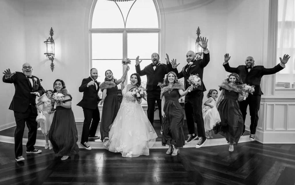 The bride, groom, bridesmaids, and groomsmen jump in excitement for a fun wedding portrait at The Park Savoy Estate.