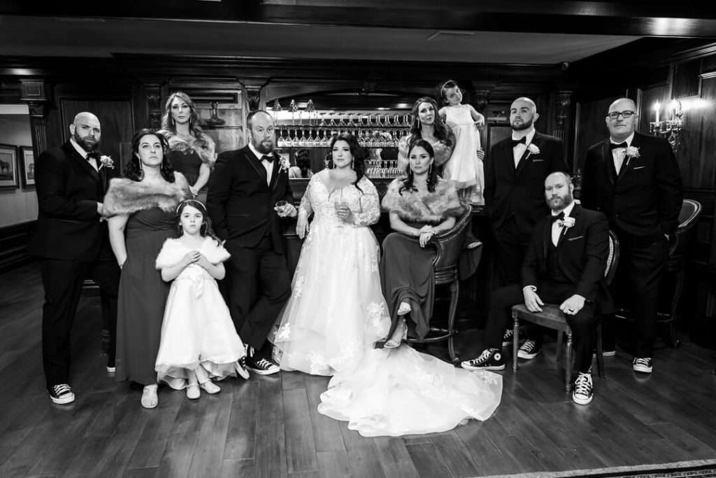 A wedding party poses in an elegant bar setting at The Park Savoy Estate, with serious expressions capturing a stylish and timeless moment.