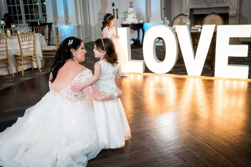 Bride and flower girl share an intimate conversation on the ballroom floor of The Park Savoy, with warm lighting and decor enhancing the moment.