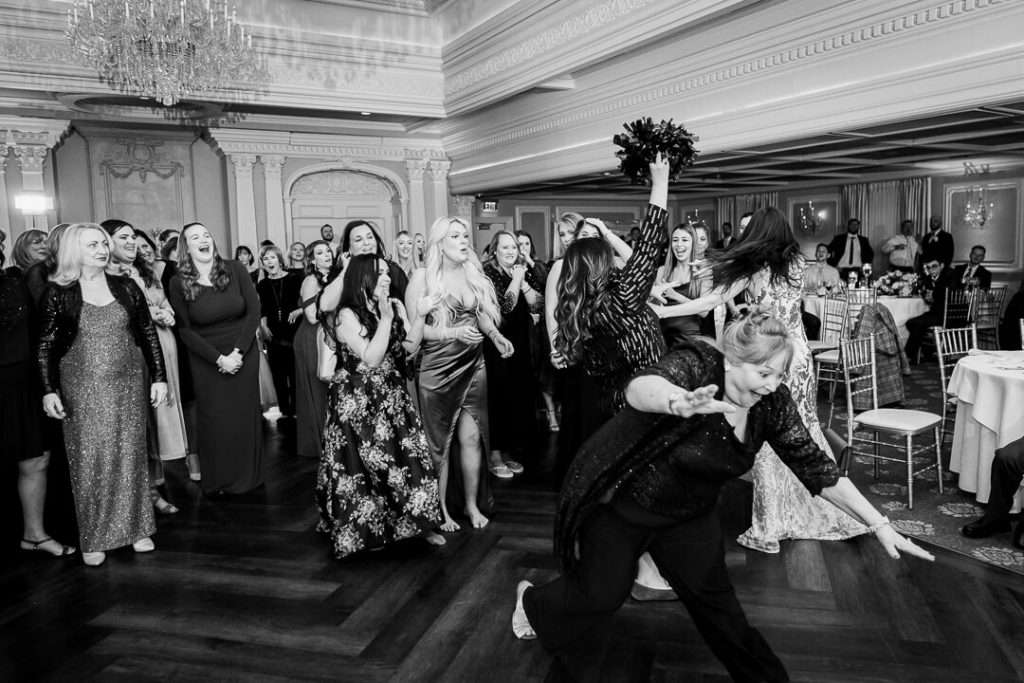 Excited guests reach for the bride’s bouquet during the bouquet toss at The Park Savoy, with joyful expressions and movement captured mid-air.