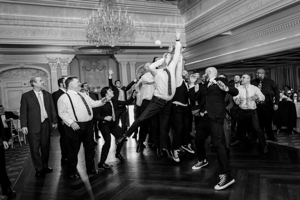 A group of energetic male guests leap into the air in competition for the garter toss at The Park Savoy’s grand ballroom.