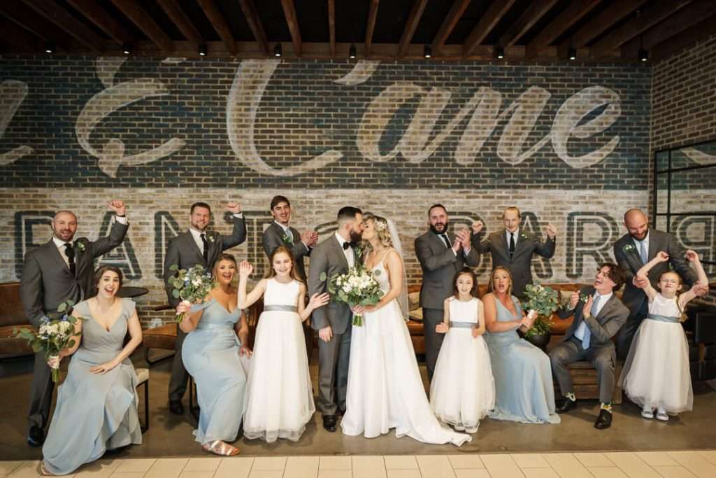 Bride and groom celebrating with their wedding party in a fun group shot at Stone House at Stirling Ridge.