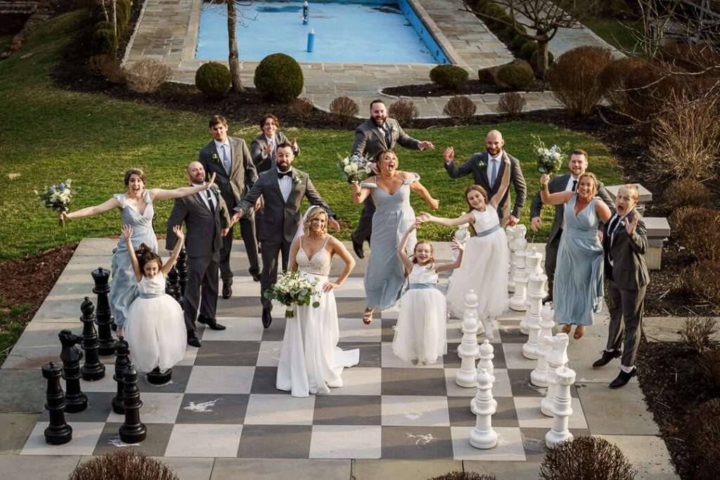 Bride and groom surrounded by their joyful wedding party, laughing and celebrating at Stone House at Stirling Ridge.