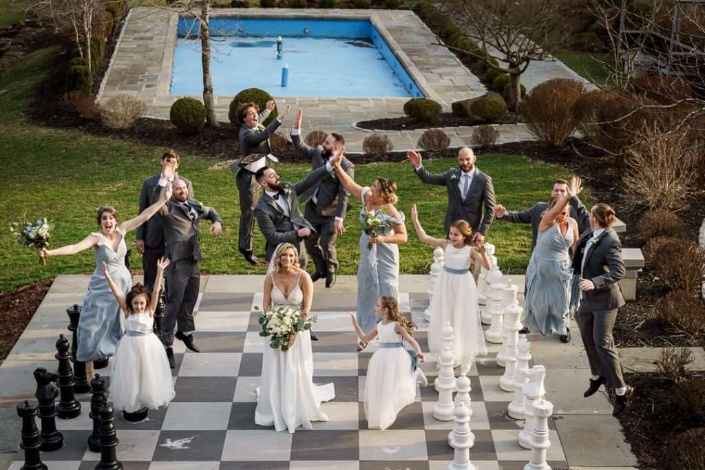 Candid joyful moment of the wedding party cheering on the outdoor chessboard at Stone House at Stirling Ridge.