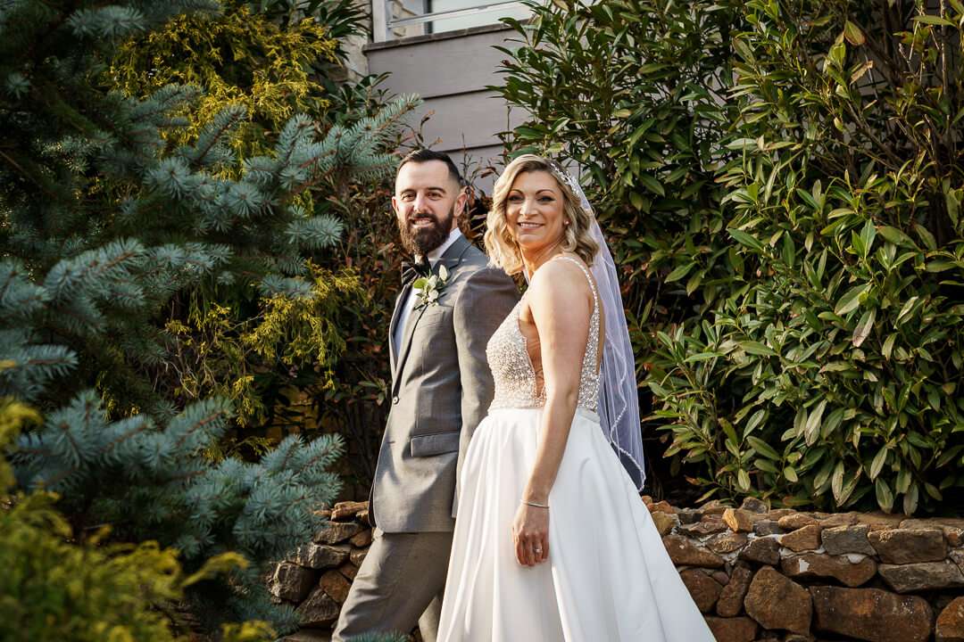 Bride and groom standing together in front of a modern water feature at Stone House at Stirling Ridge.