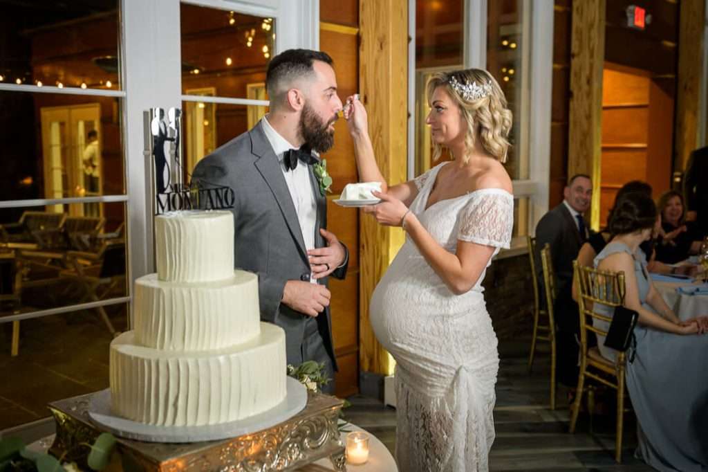 Bride feeding groom a piece of cake during the reception, sharing a playful moment at Stone House at Stirling Ridge.