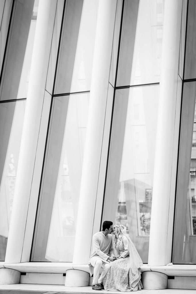 Candid black and white photo of couple sitting and sharing a kiss outside the Oculus