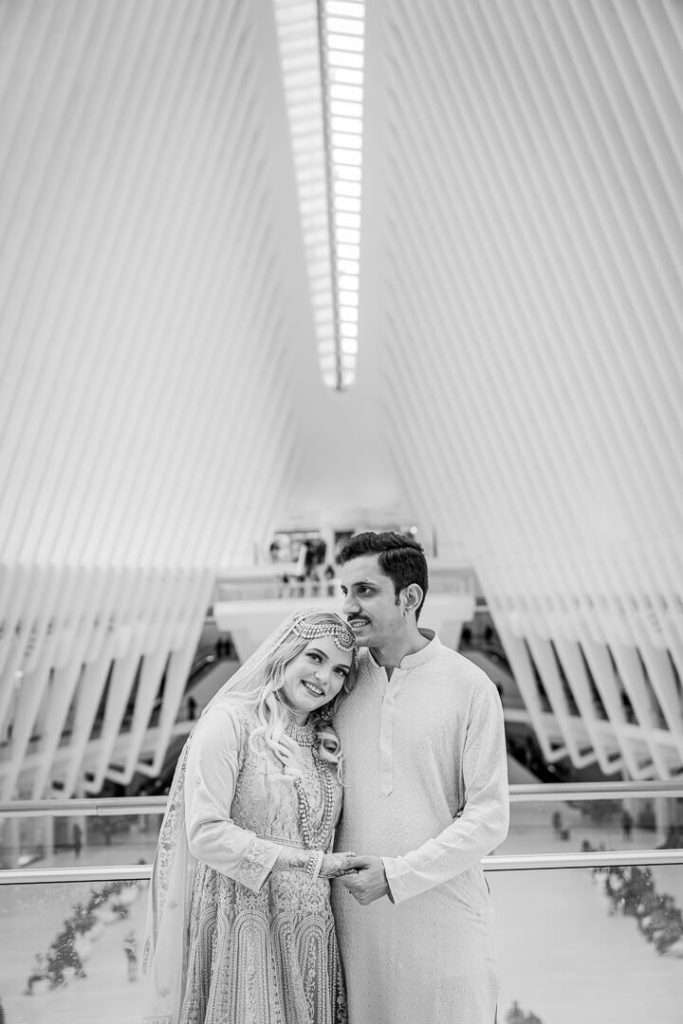 Smiling couple in black and white engagement photo at the Oculus with architectural symmetry.