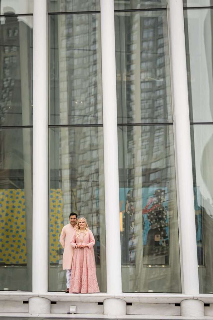 Couple framed by tall glass panels in a modern engagement portrait at the Oculus NYC