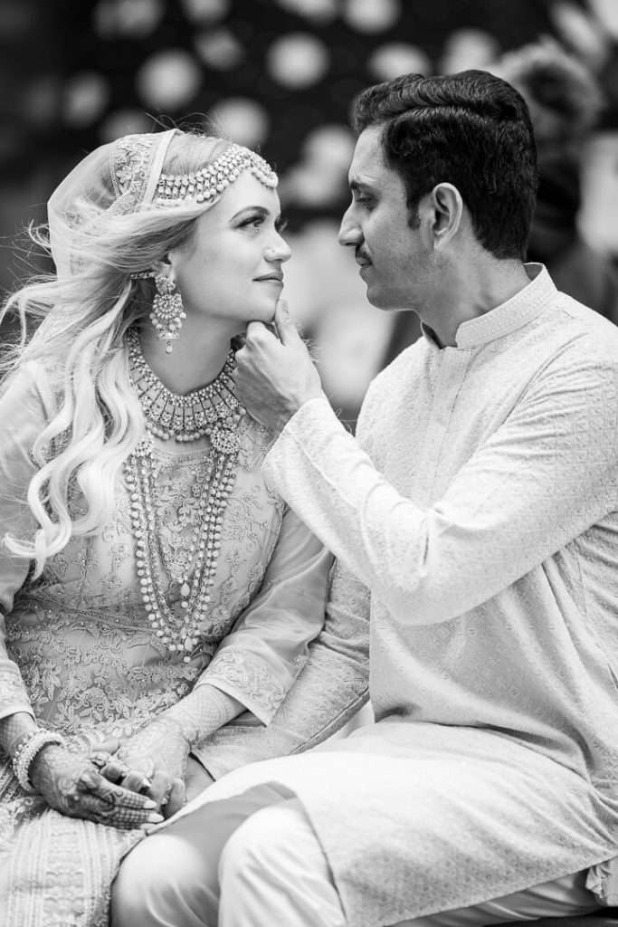 Black and white intimate portrait of groom gently touching bride’s chin at the Oculus