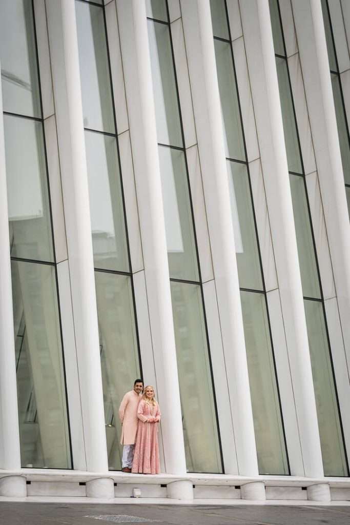 Engagement photo of couple standing against the tall vertical beams of the Oculus architecture in NYC.