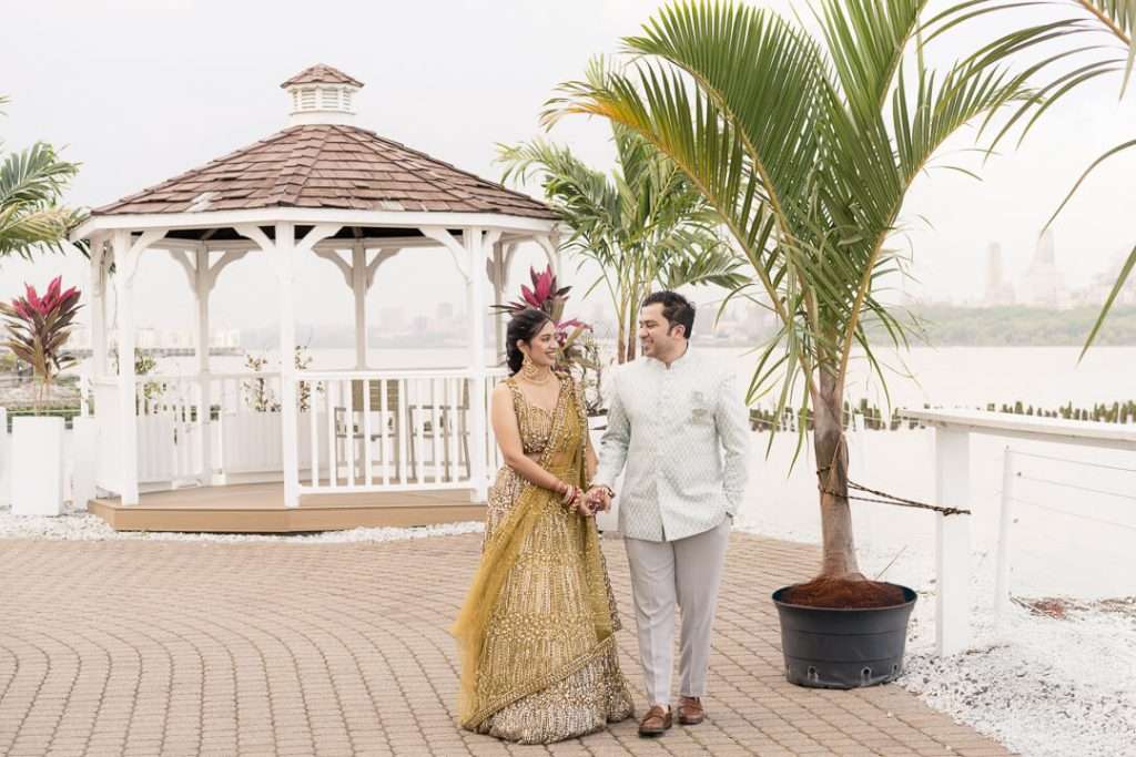 Bride and groom walking hand-in-hand by gazebo at Waterside Restaurant North Bergen NJ with city views

