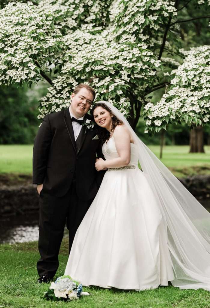 Bride and groom hugging under flowering tree during wedding portraits in Nutley, NJ