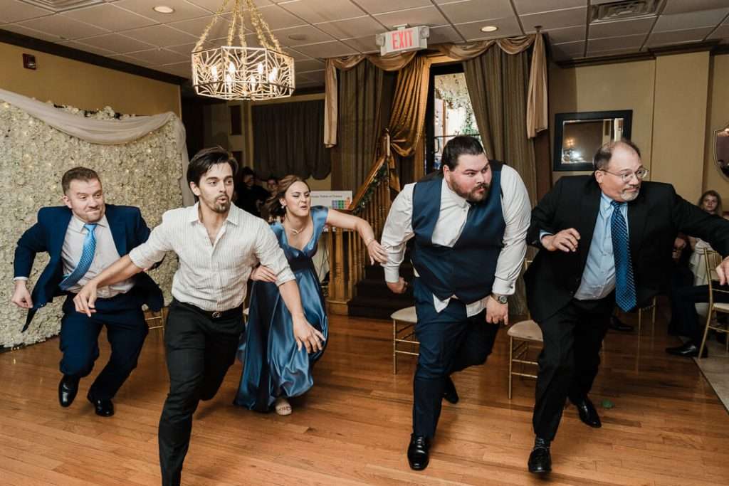 Wedding guests sprinting in playful competition during fun reception moment in Nutley, NJ