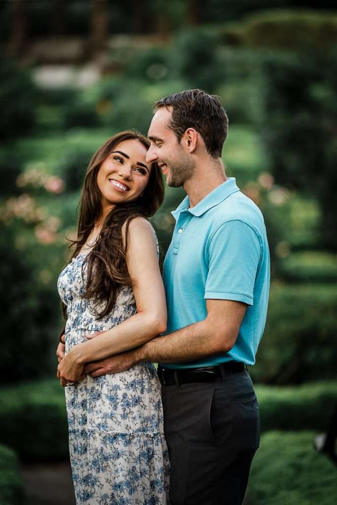 Engaged couple smiling and embracing during a romantic photo session at Deep Cut Gardens in New Jersey.