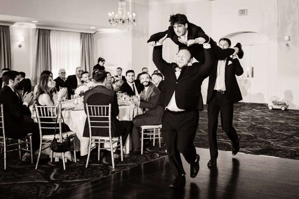 Groomsmen make a lively entrance to the reception, dancing their way into the ballroom at The Mansion at Mountain Lakes.