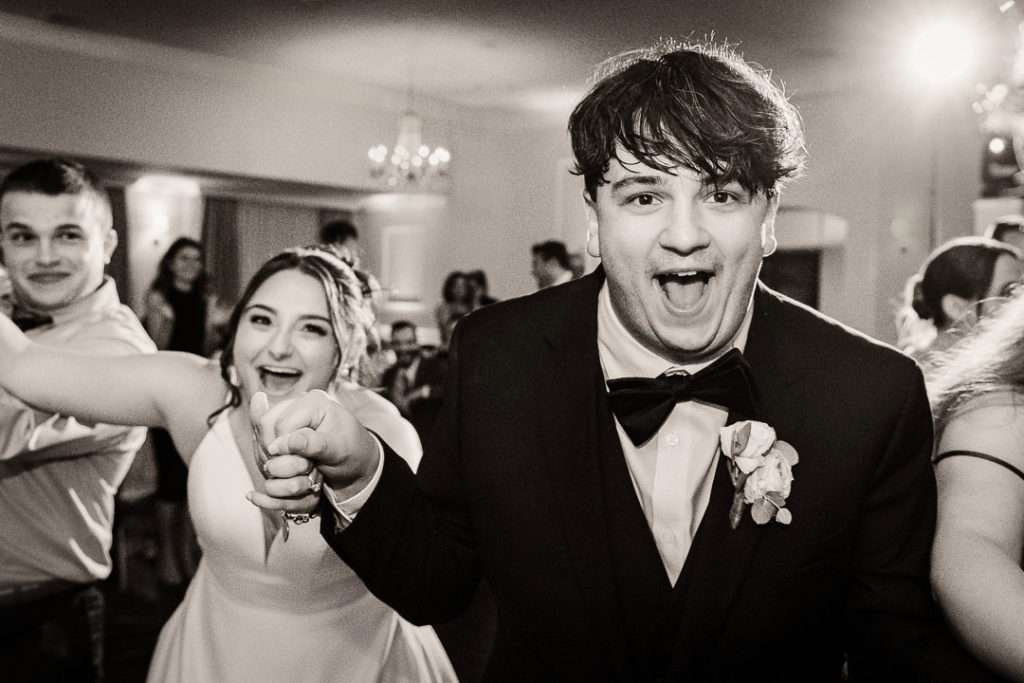 Bride and groom dancing joyfully together during their wedding reception at The Mansion at Mountain Lakes.