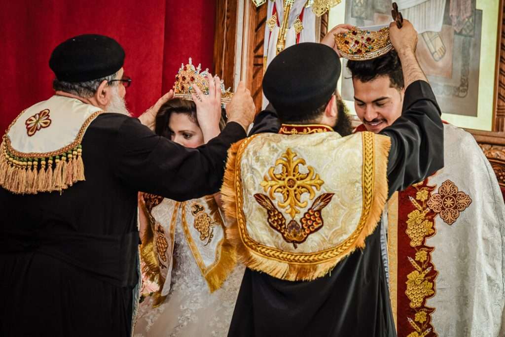 Coptic Orthodox priests place crowns on bride and groom during traditional wedding rite.