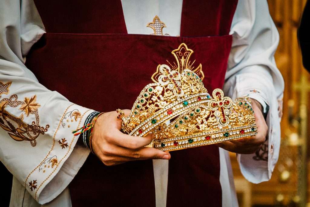 Close-up of ornate gold Coptic wedding crowns held by priest during ceremony in New Jersey