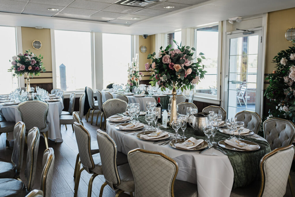 Elegant reception setup at The Armory NJ Restaurant in Perth Amboy with tall blush and burgundy floral centerpieces, gold accents, and waterfront views captured by Alex Kaplan Photography.