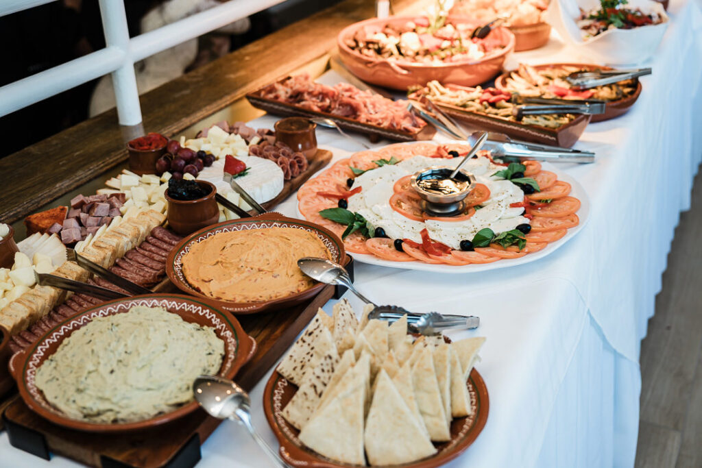 Elegant appetizer spread featuring hummus, pita, fresh mozzarella, tomato, and charcuterie arranged on rustic wooden boards at The Armory NJ Restaurant in Perth Amboy, photographed by Alex Kaplan Photography.