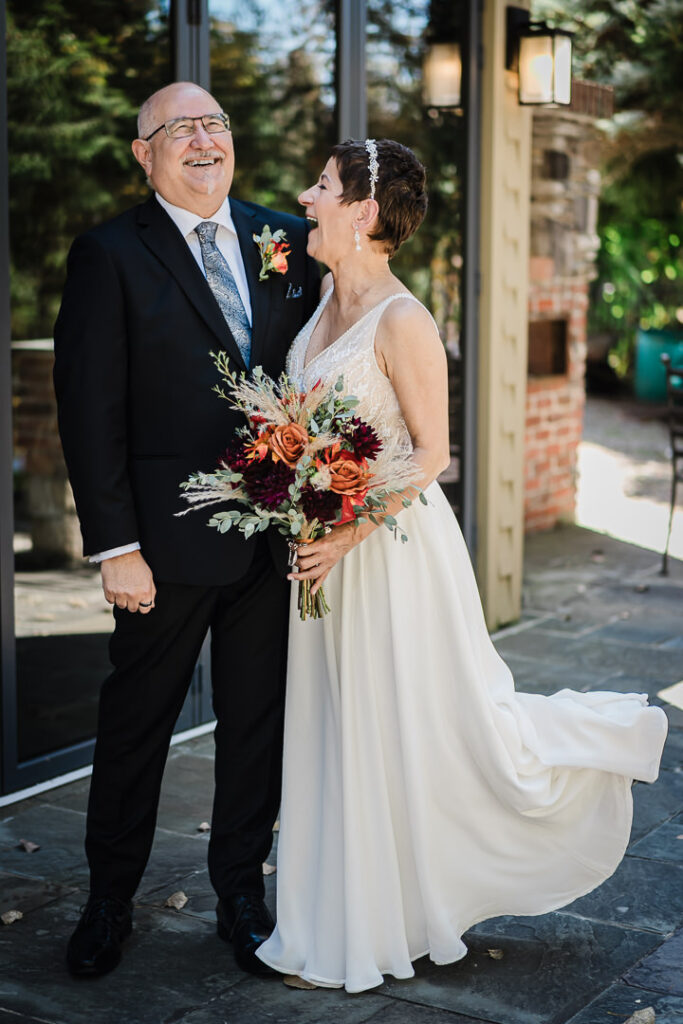 Bride laughing with her father during portraits at Mohawk House’s outdoor patio area.