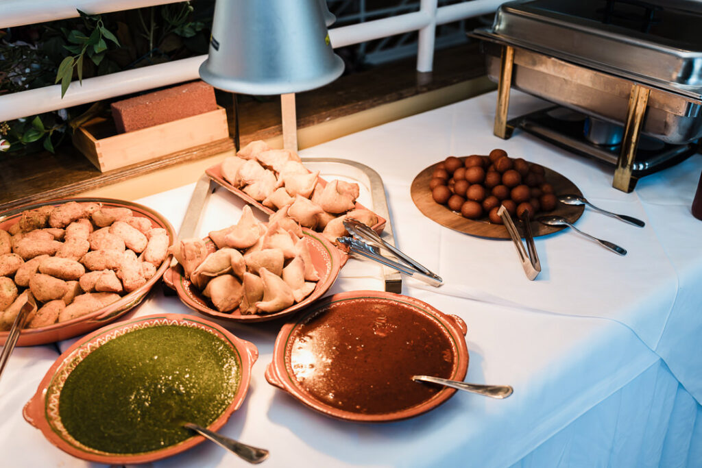 Appetizer table featuring samosas, fritters, and traditional Indian sauces including green chutney and tamarind dip, beautifully arranged at The Armory NJ Restaurant in Perth Amboy, photographed by Alex Kaplan Photography.
